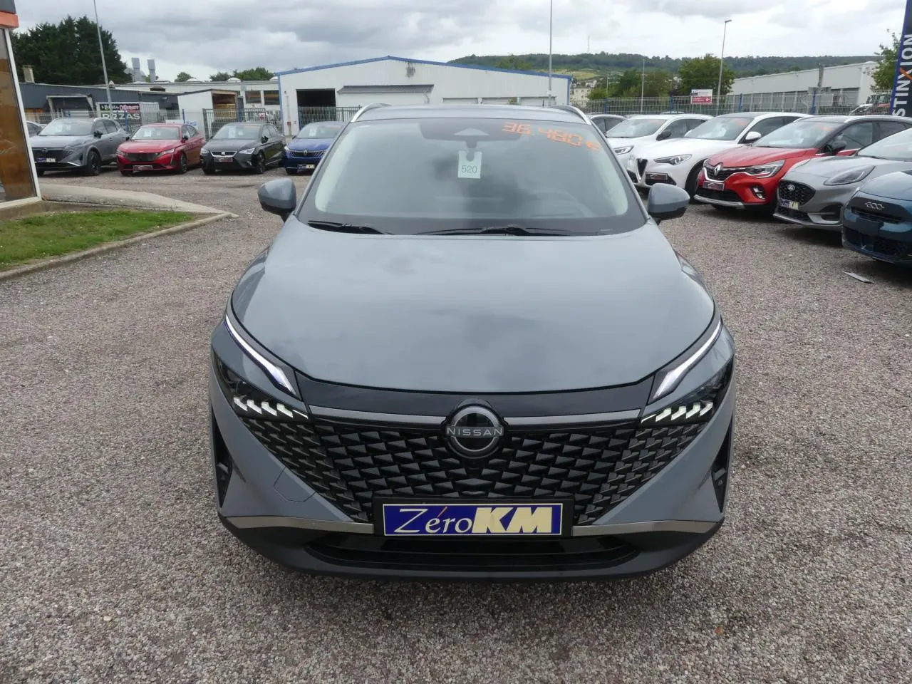 Vue frontale d'un Nissan Qashqai 1.5 e-Power gris métallisé avec calandre noire et feux LED distinctifs.