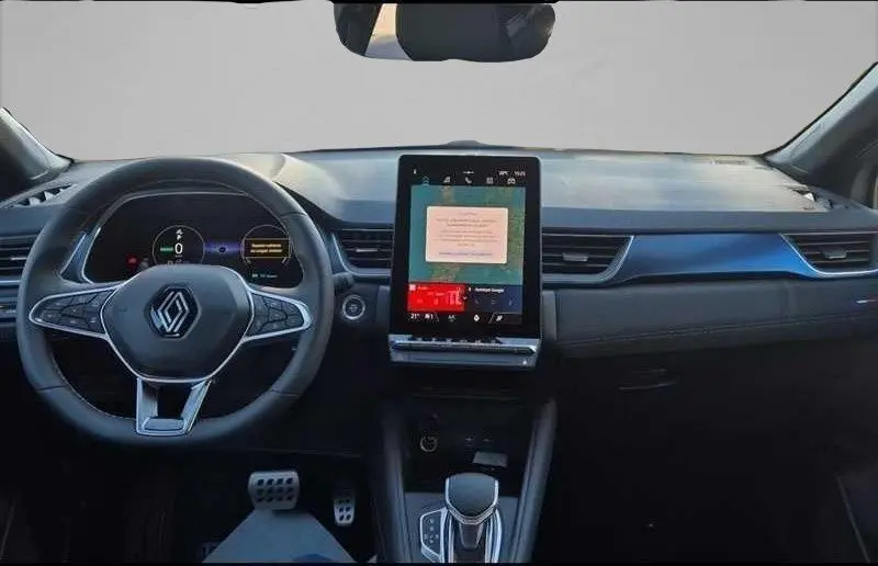 Vue intérieure avant du Renault Captur E-Tech hybride 2025, tableau de bord noir avec écran tactile vertical central et volant multifonction.