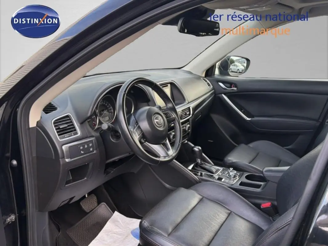 Intérieur noir du Mazda CX-5 2017 vu côté conducteur, avec volant multifonction et console centrale moderne.