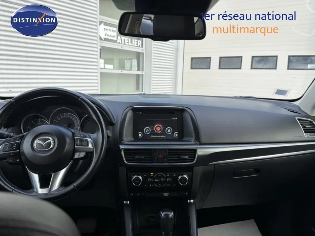 Vue intérieure frontale du tableau de bord noir du Mazda CX-5 2017 avec écran central et volant multifonction.