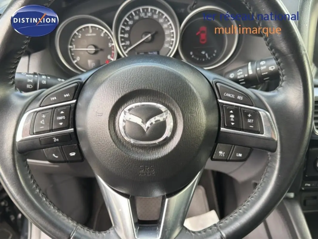 Gros plan sur le volant multifonction noir du Mazda CX-5 2017 avec commandes intégrées et tableau de bord visible.