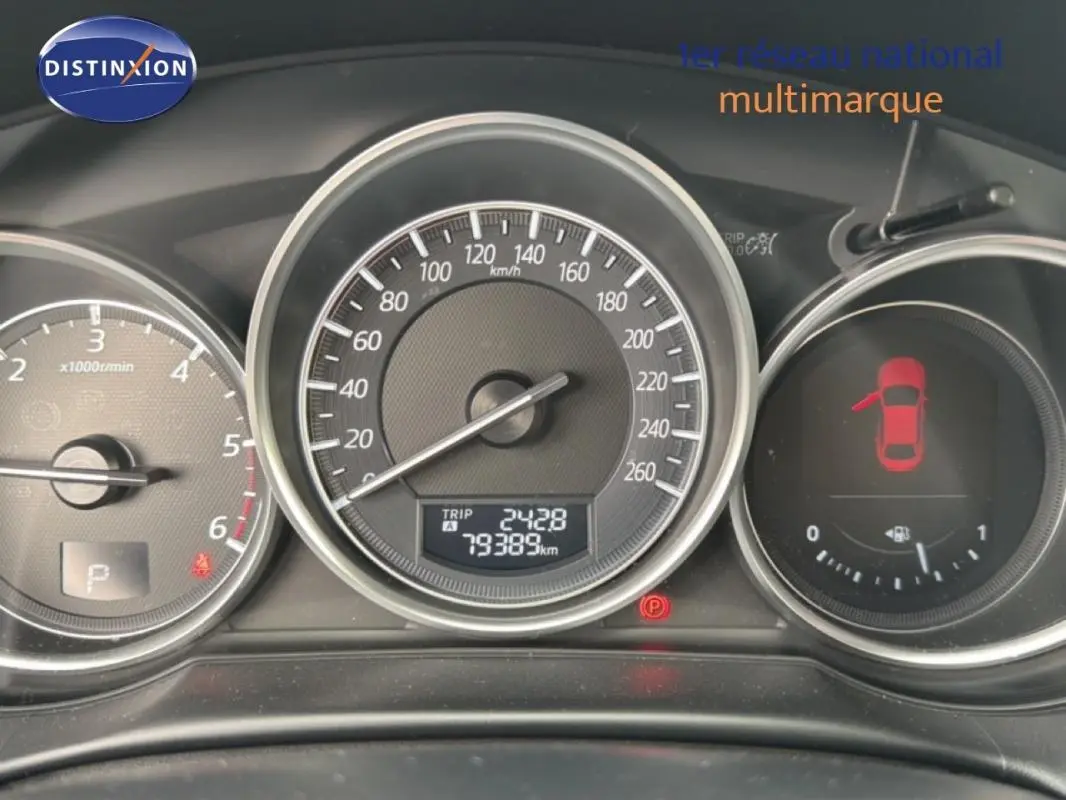 Tableau de bord du Mazda CX-5 noir 2017 montrant compte-tours, vitesse et niveau carburant avec porte ouverte à gauche.