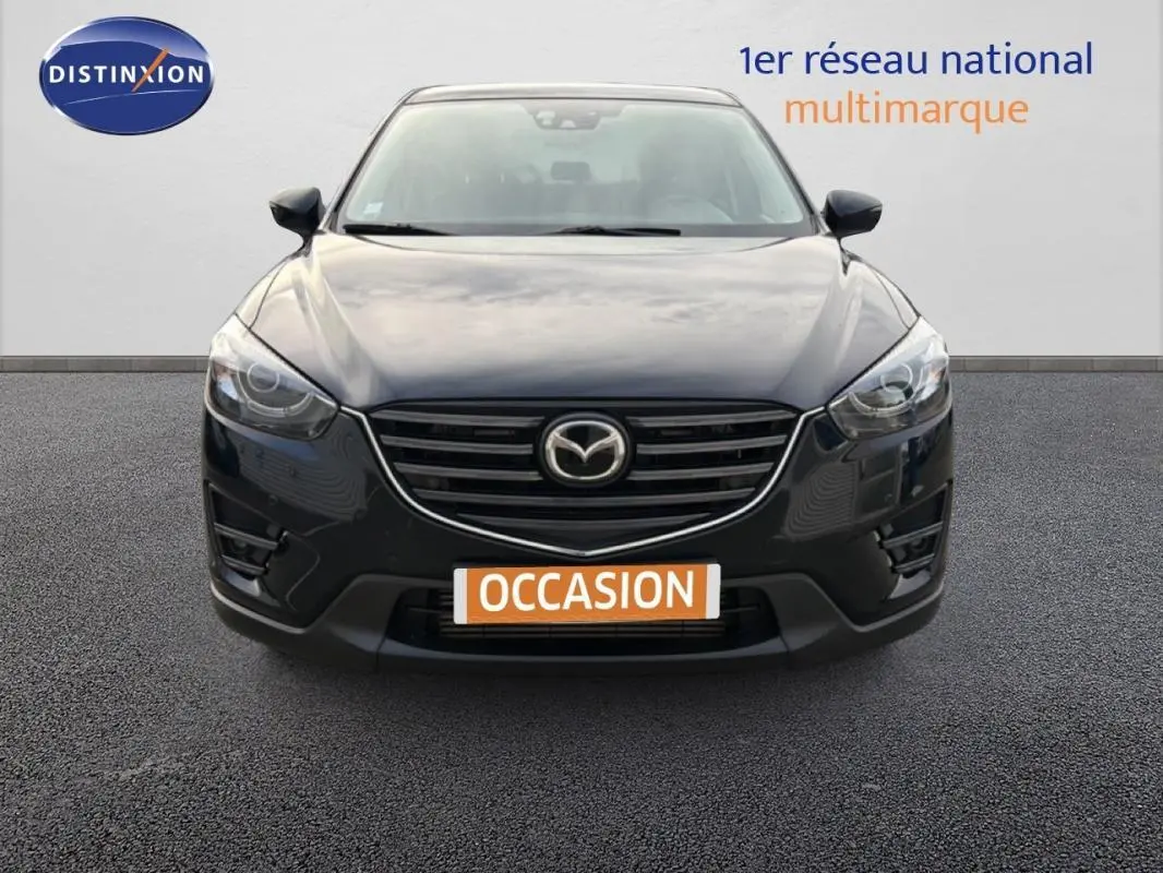 Vue frontale d'un Mazda CX-5 noir 2017 avec calandre chromée et phares LED allumés sur parking.