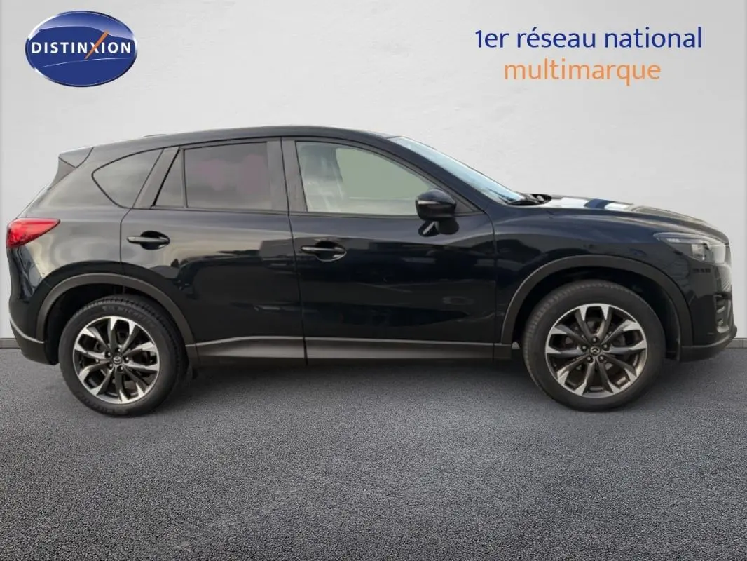 Profil côté gauche d'un Mazda CX-5 noir de 2017 avec jantes alliage 19 pouces et attelage fixe visible.