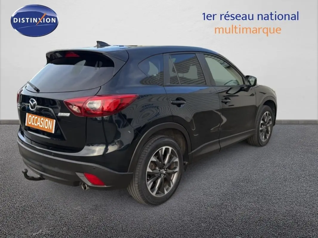 Vue 3/4 arrière droite d'un Mazda CX-5 noir 2017 avec jantes alliage 19 pouces et attelage fixe visible.