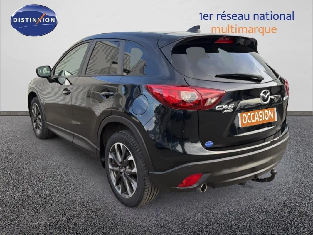 Vue 3/4 arrière droite d'un Mazda CX-5 noir 2017 avec jantes alliage 19 pouces et attelage fixe visible.