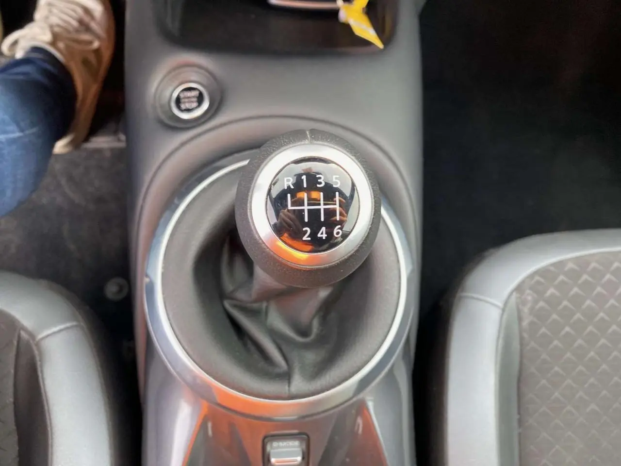 Le levier de vitesses manuel du Nissan Juke 2024 en gros plan, entouré de sièges gris.