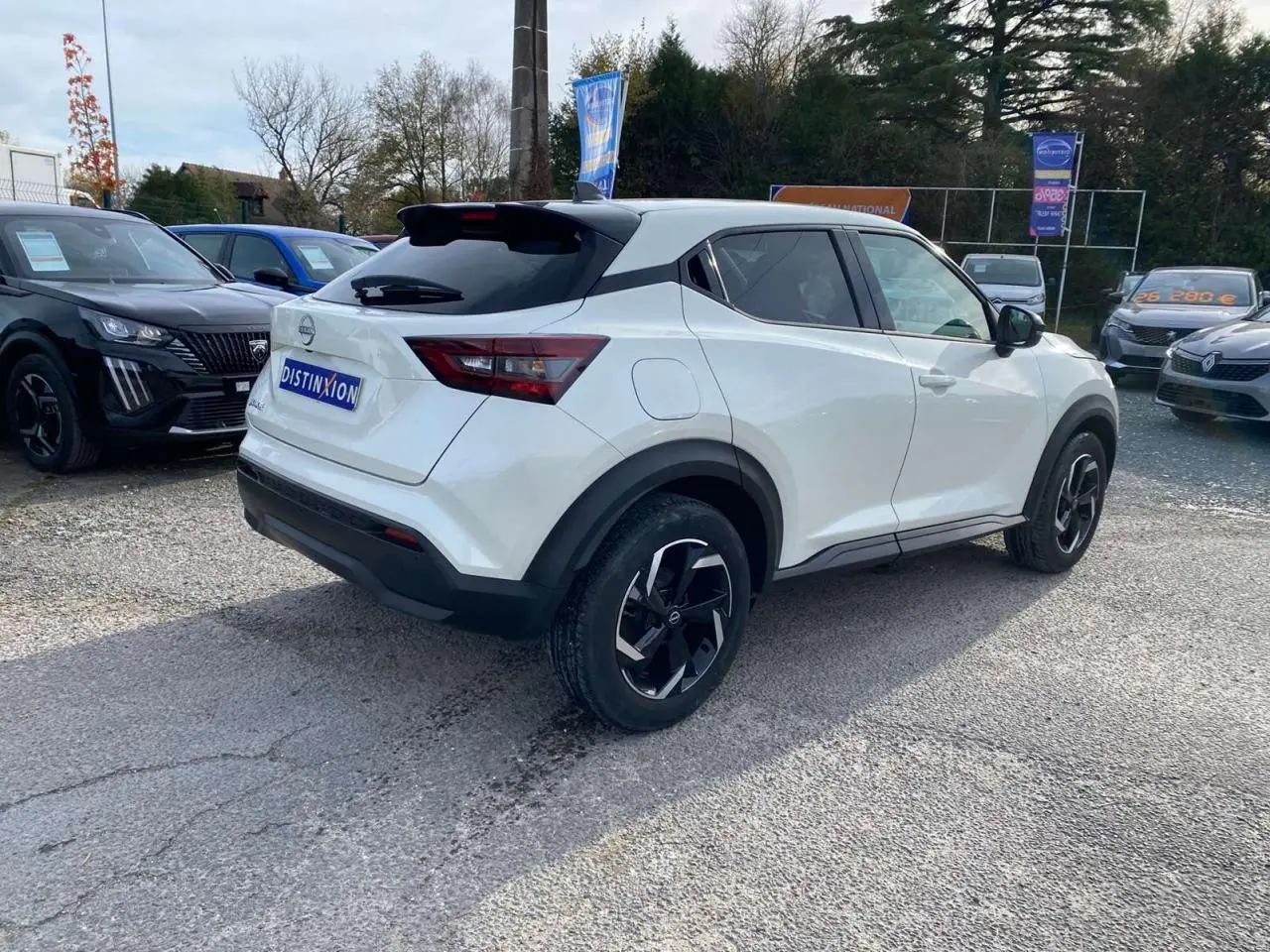 Nissan Juke blanc perle vu en 3/4 arrière droit, avec jantes noires et toit noir contrastant.