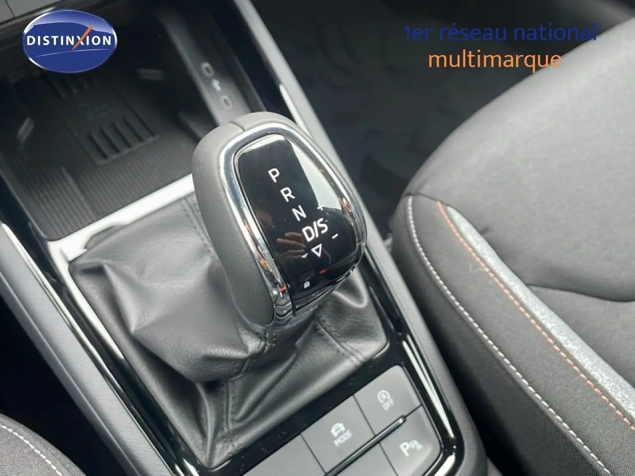 Le levier de vitesse automatique DSG7 de la Skoda Kamiq 2025 en gros plan avec sellerie tissu gris et surpiqûres orange.