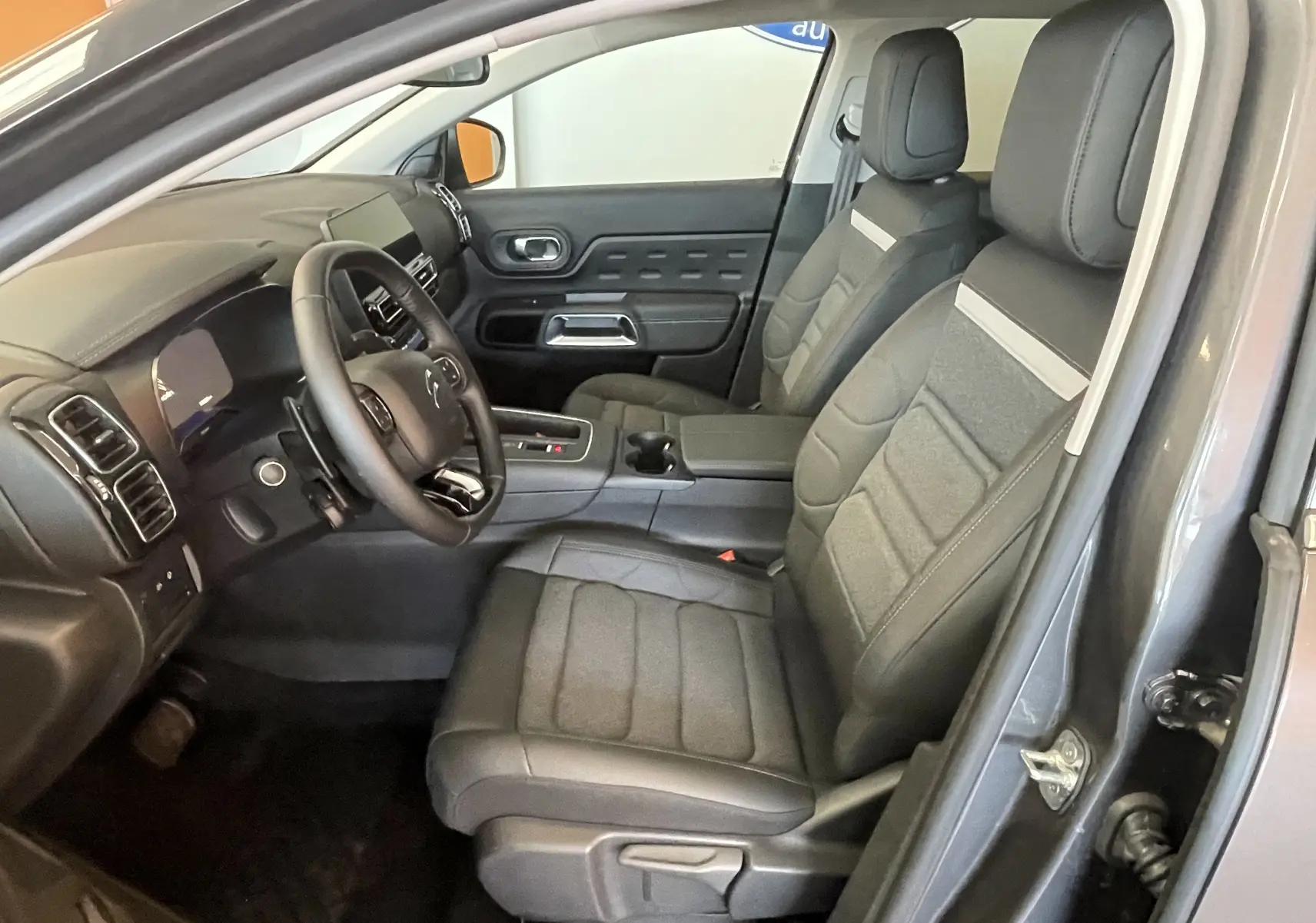 Vue intérieure côté conducteur du Citroën C5 Aircross hybride bleu Eclipse, avec sièges tissu/TEP et volant cuir.