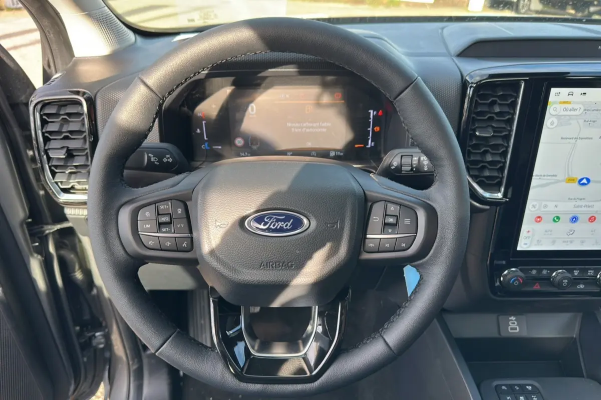 Vue rapprochée du volant cuir multifonctions et tableau de bord numérique du Ford Ranger gris carbone 2026.