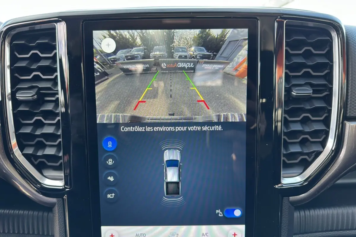 Vue rapprochée de l'écran central du Ford Ranger gris carbone montrant la caméra de recul et les capteurs de stationnement.