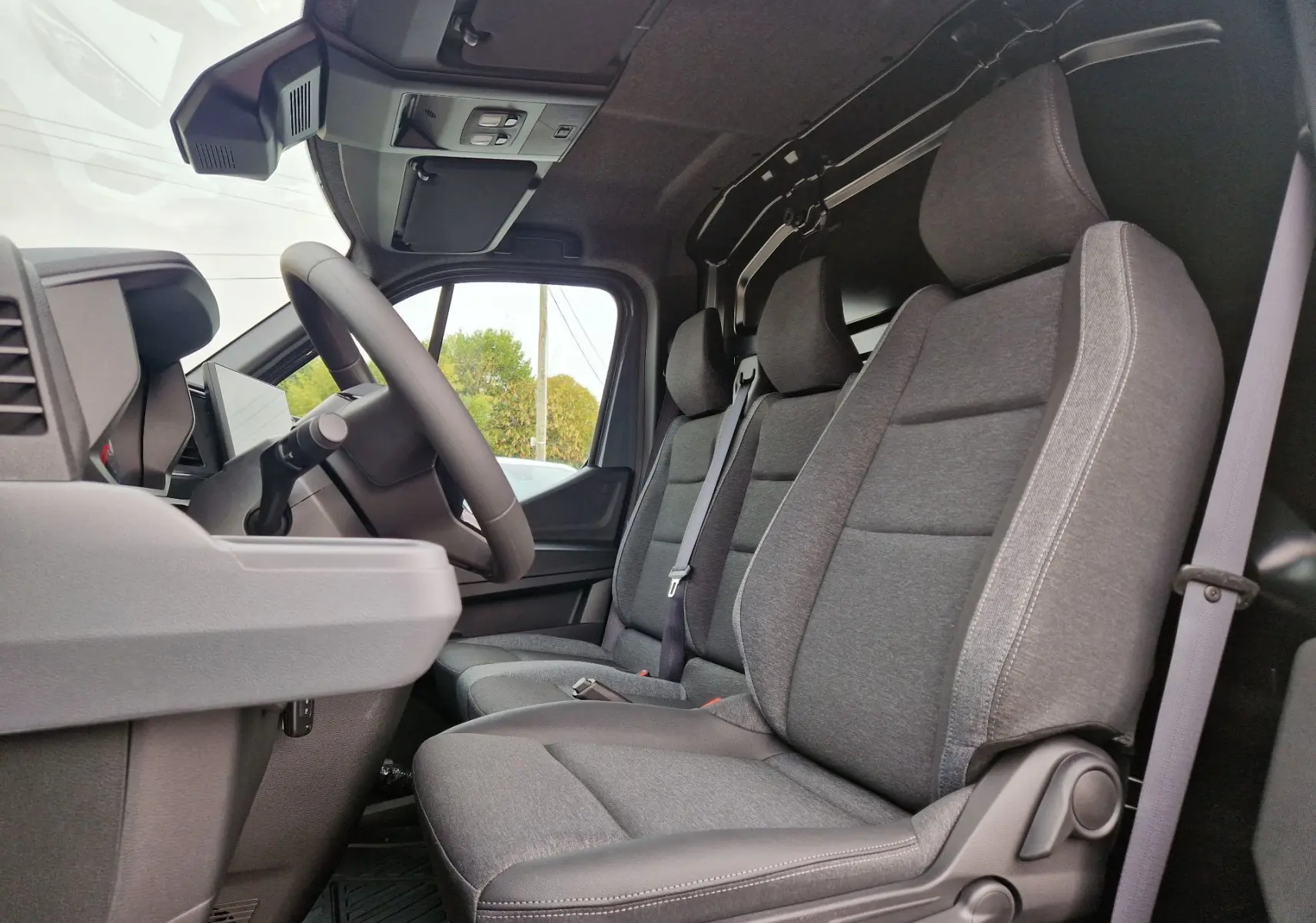 Vue intérieure côté conducteur du Renault Master 2026, montrant les sièges gris et la cloison séparatrice derrière.
