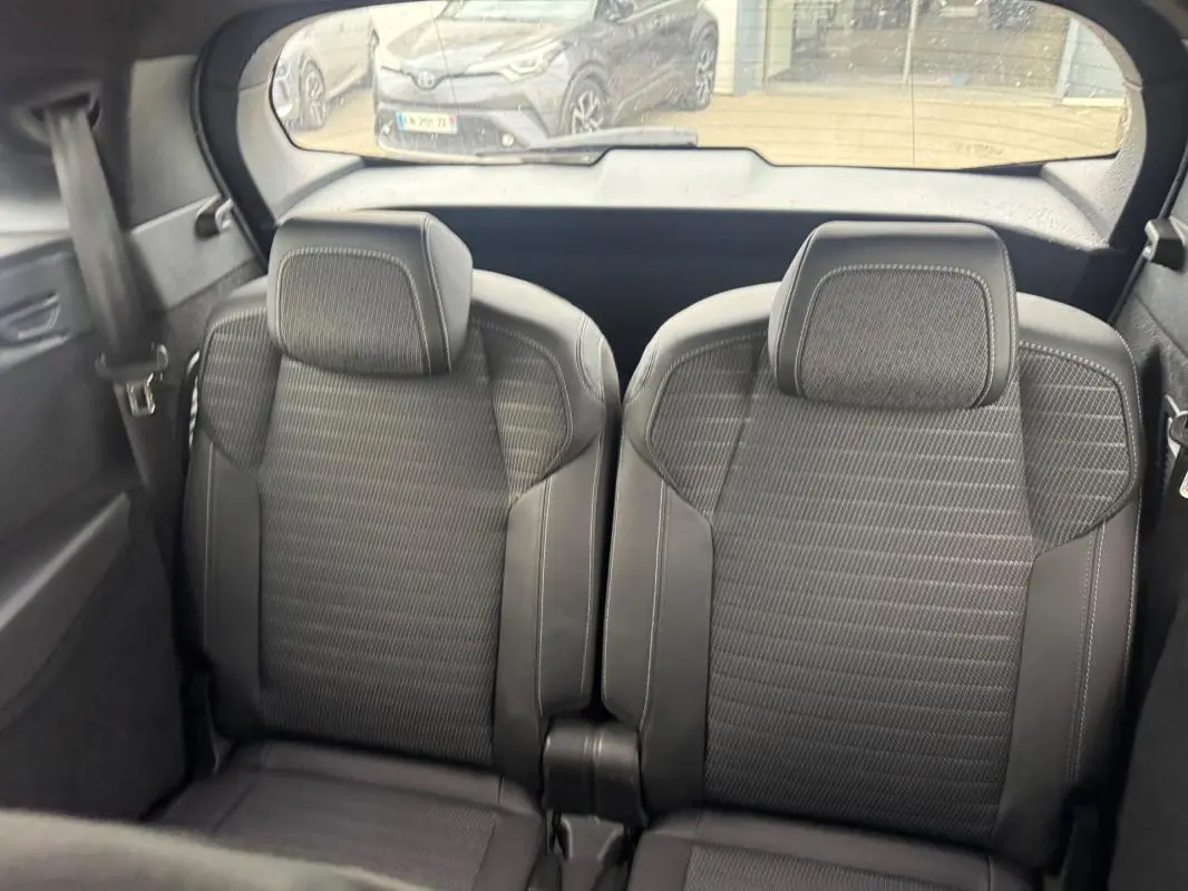 Vue arrière intérieure des deux sièges noirs du Peugeot 5008 Hybrid 145 ch e-DCS6 GT avec appuie-têtes intégrés.