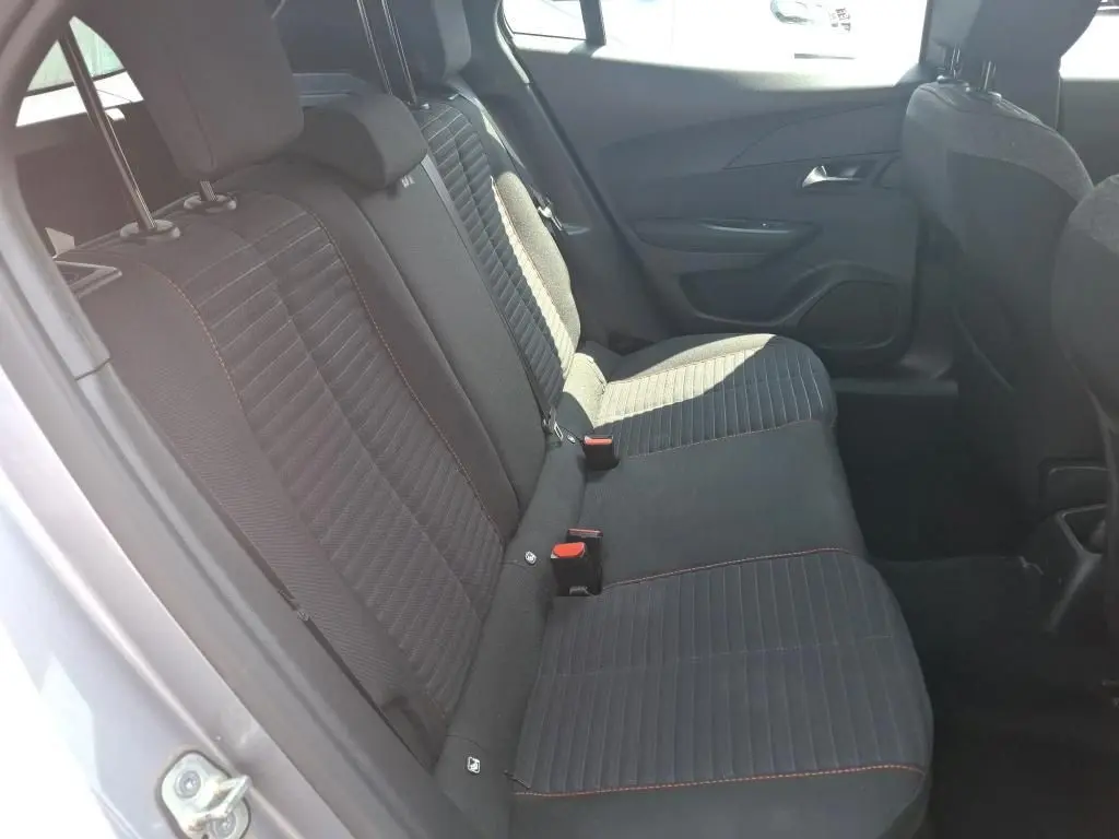 Peugeot 2008 gris Artense vue de profil côté gauche, avec toit noir et jantes alliage, stationnée sur un terrain gravillonné.