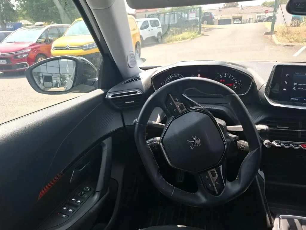 Vue intérieure côté conducteur du Peugeot 2008 gris Artense 2022, sièges tissu noir et tableau de bord moderne.