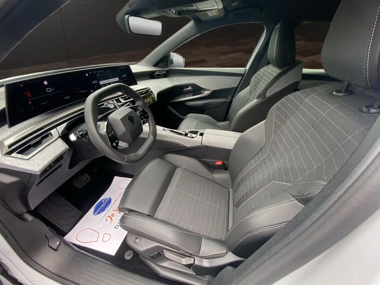 Intérieur avant droit du Peugeot 3008 2024, sièges tissu noir et gris, tableau de bord numérique large et moderne.