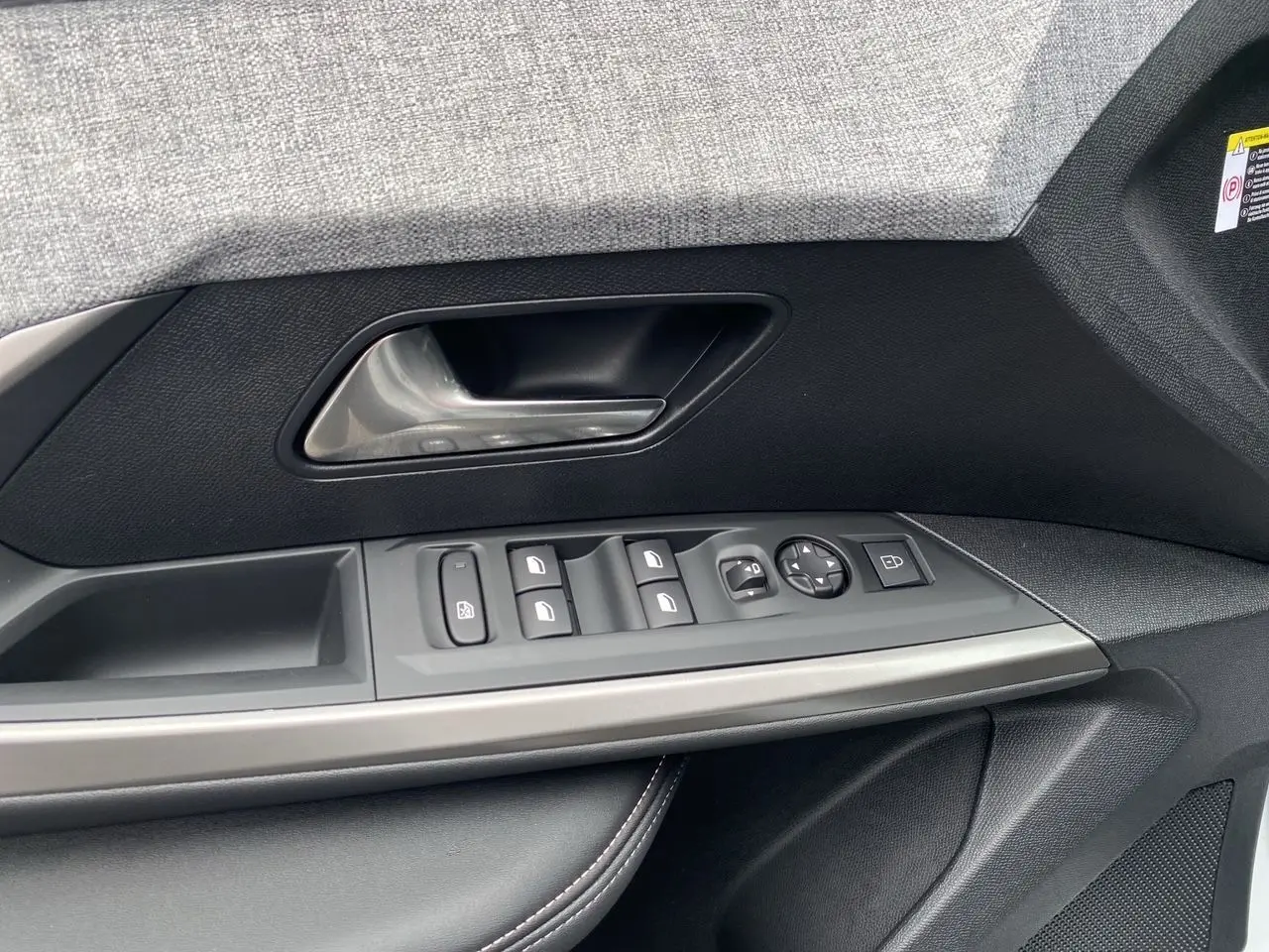 Gros plan sur la commande de porte côté gauche du Peugeot 3008 blanc Okenite, mettant en valeur les boutons de réglage des vitres et des rétroviseurs.