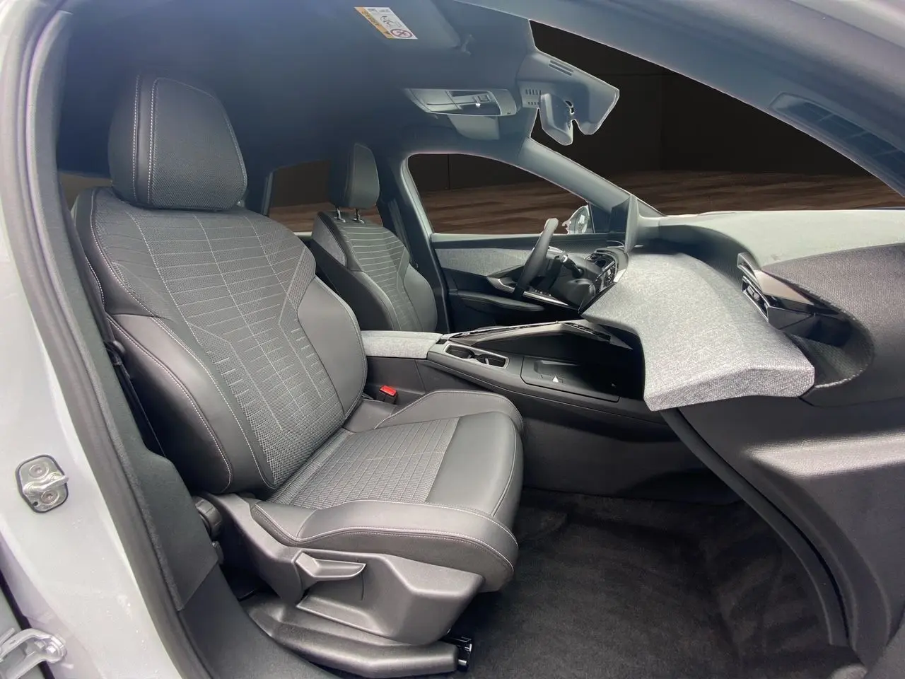 Vue intérieure côté gauche du Peugeot 3008 blanc Okenite 2024, sièges tissu et cuir gris avec tableau de bord moderne.