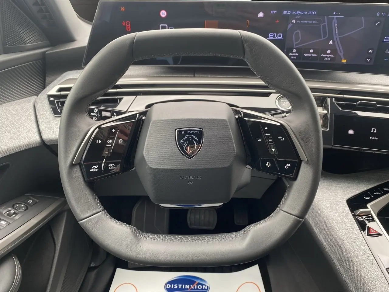 Volant cuir noir au design carré du Peugeot 3008 hybride 2024 avec tableau de bord numérique et écran tactile visible.