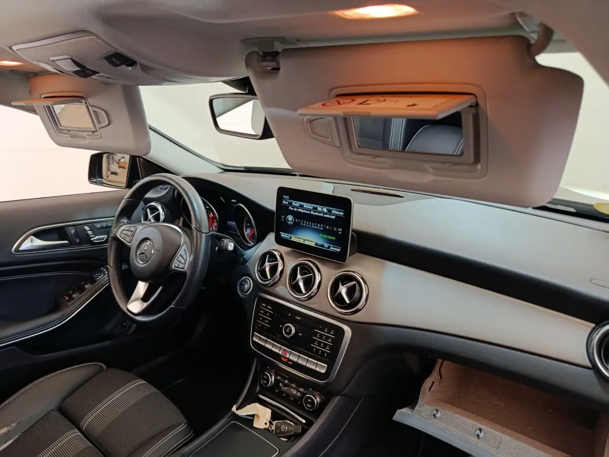 Vue intérieure côté conducteur du tableau de bord noir et gris du Mercedes GLA 220 d avec écran central et volant cuir multifonctions.