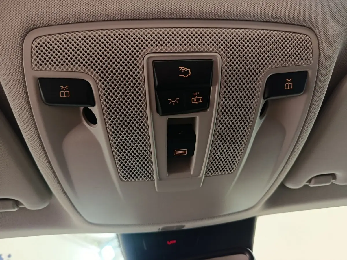 Vue en contre-plongée du panneau de commandes plafonnier beige clair dans l'habitacle du Mercedes GLA noir 2018.