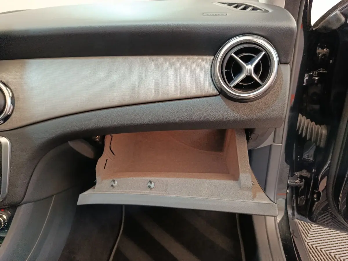 Vue intérieure côté passager du tableau de bord noir d'un Mercedes GLA 220 d 2018 avec boîte à gants ouverte.