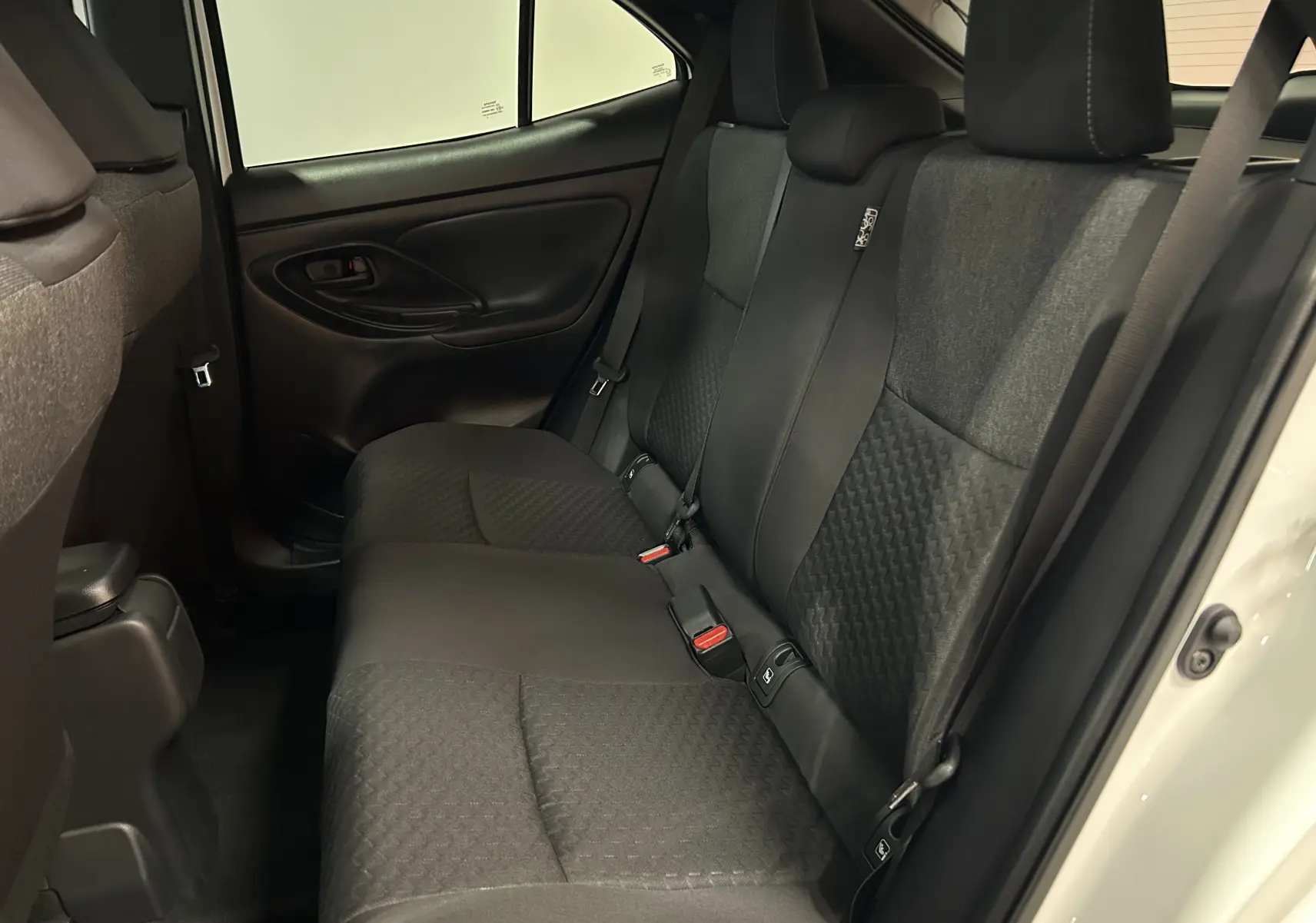 Vue intérieure côté droit des sièges arrière en tissu gris foncé du Toyota Yaris Cross blanc 2025, version 130 DESIGN.