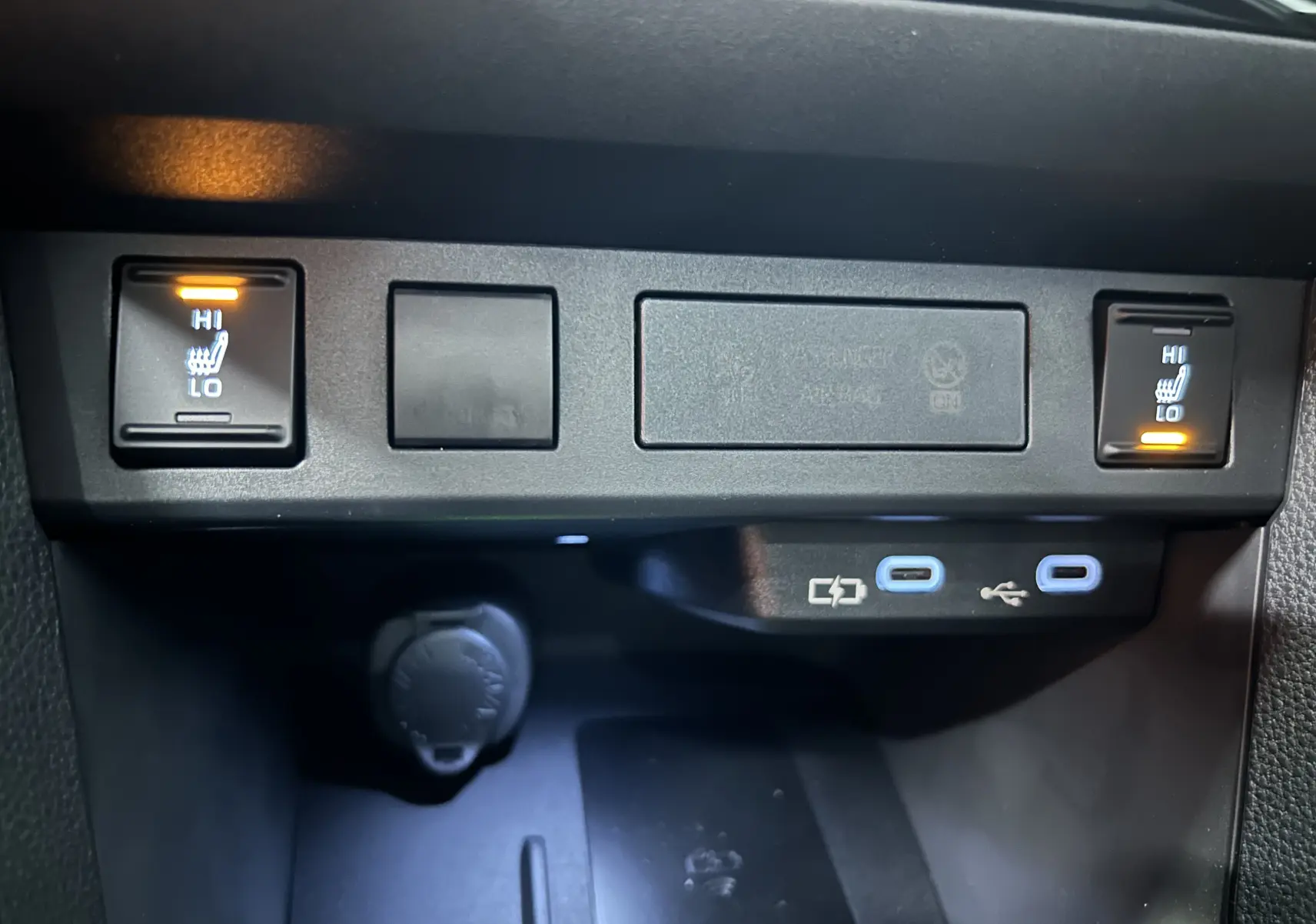 Gros plan sur les commandes des sièges chauffants avant et les ports USB-C du Toyota Yaris Cross blanc 2025.