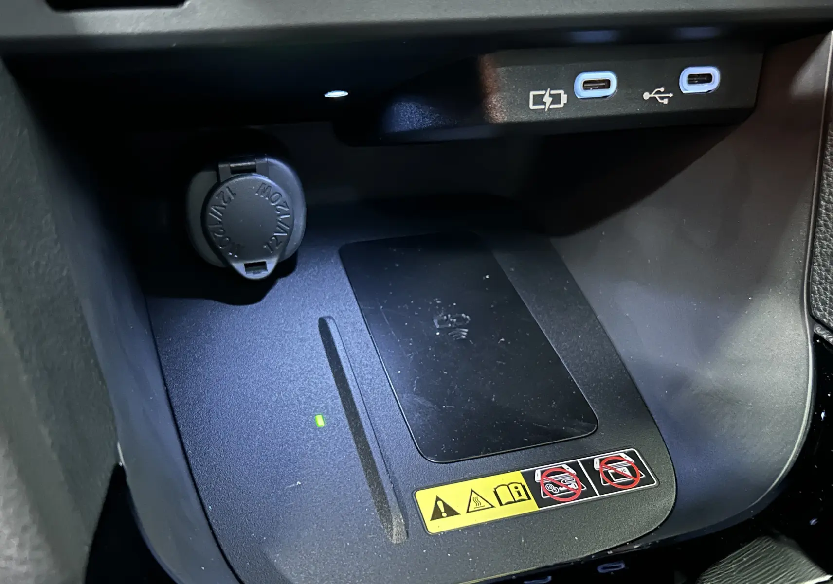 Gros plan sur la console centrale noire de la Toyota Yaris Cross 2025, montrant un chargeur sans fil et deux ports USB-C.