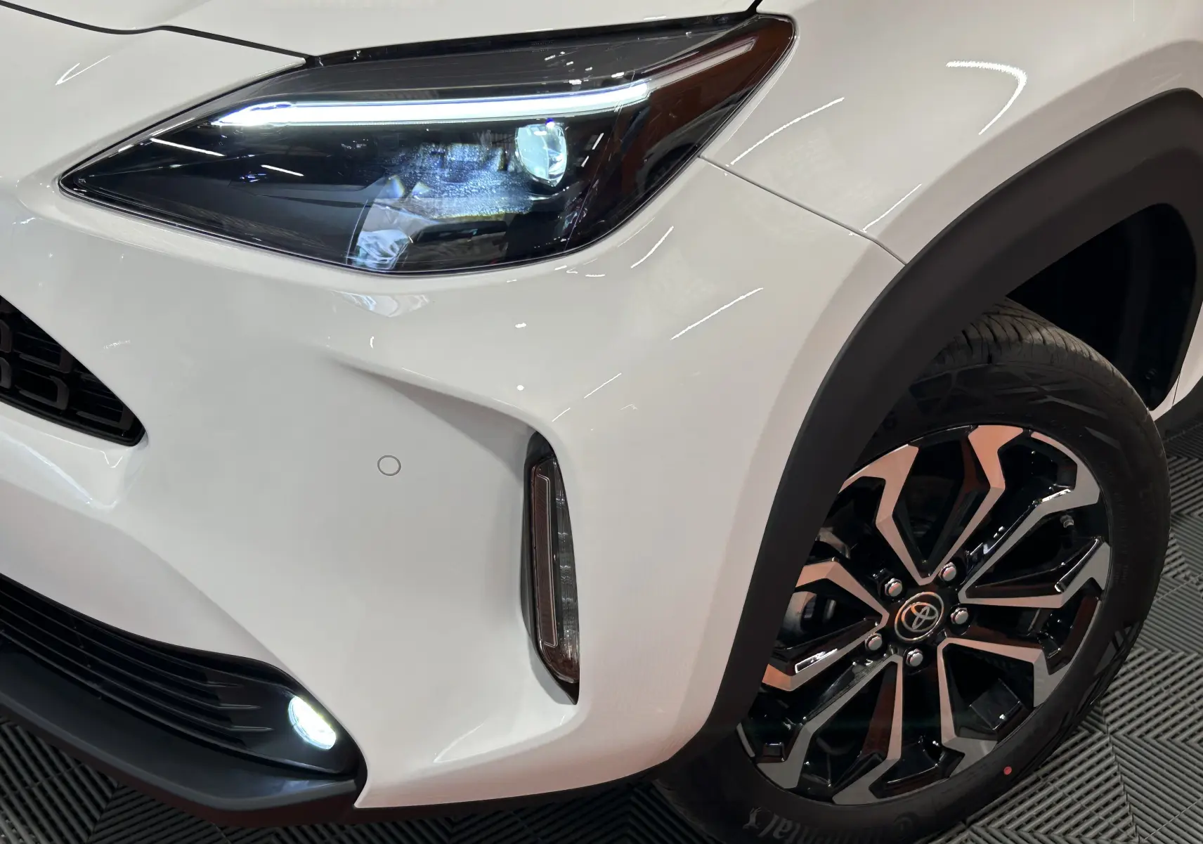 Gros plan sur l'avant droit blanc du Toyota Yaris Cross 130 Design MY25 avec phares LED et jantes alliage noires.