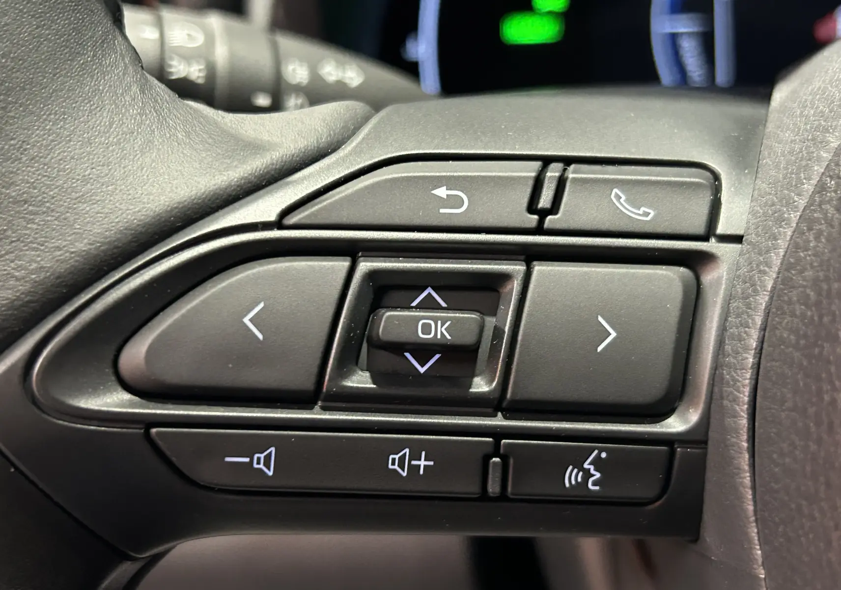 Gros plan sur les commandes au volant du Toyota Yaris Cross 130 Design blanc, avec boutons de navigation et volume.