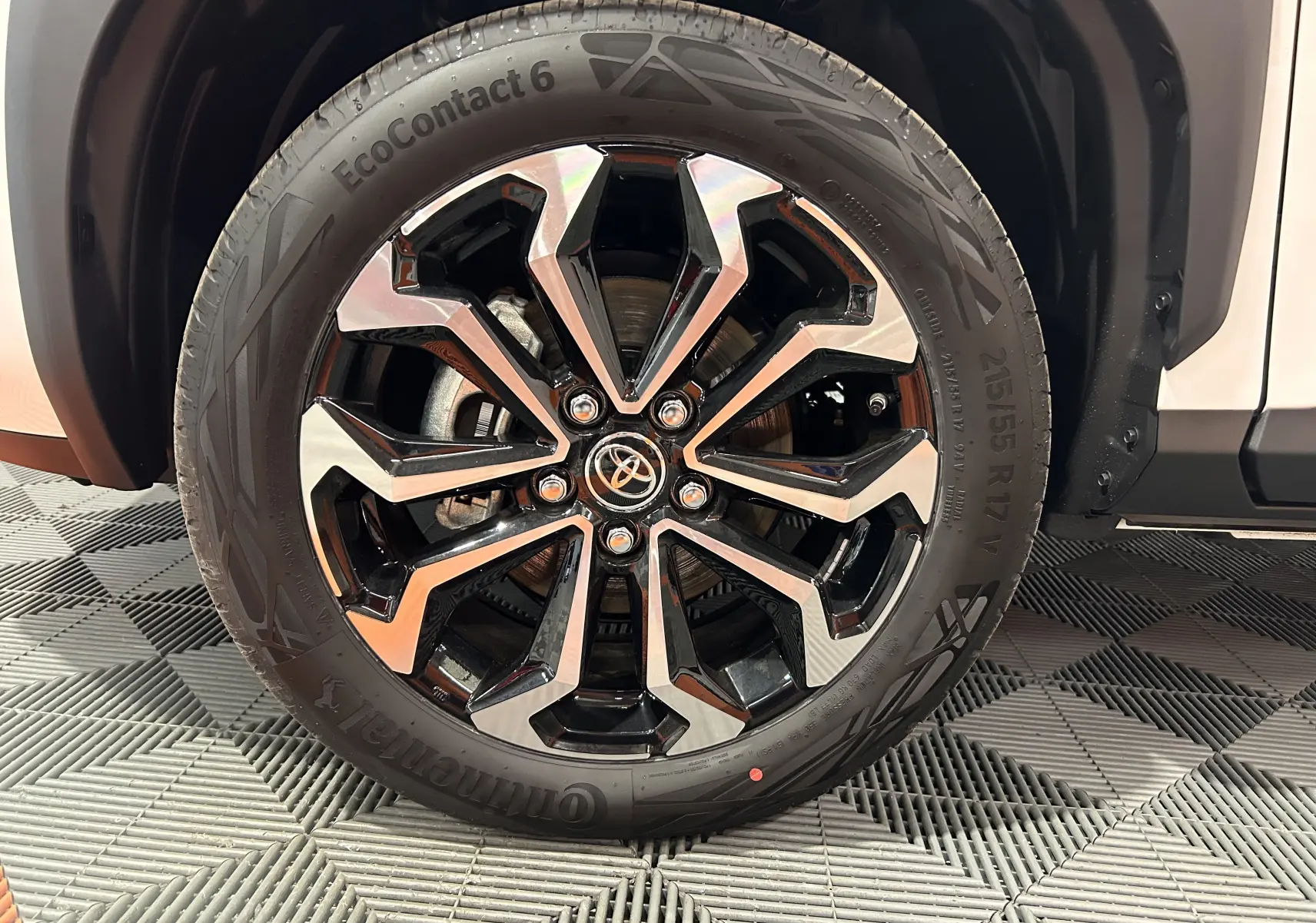 Gros plan sur la roue avant droite de la Toyota Yaris Cross blanche 2025 avec jante alliage noire et argentée.