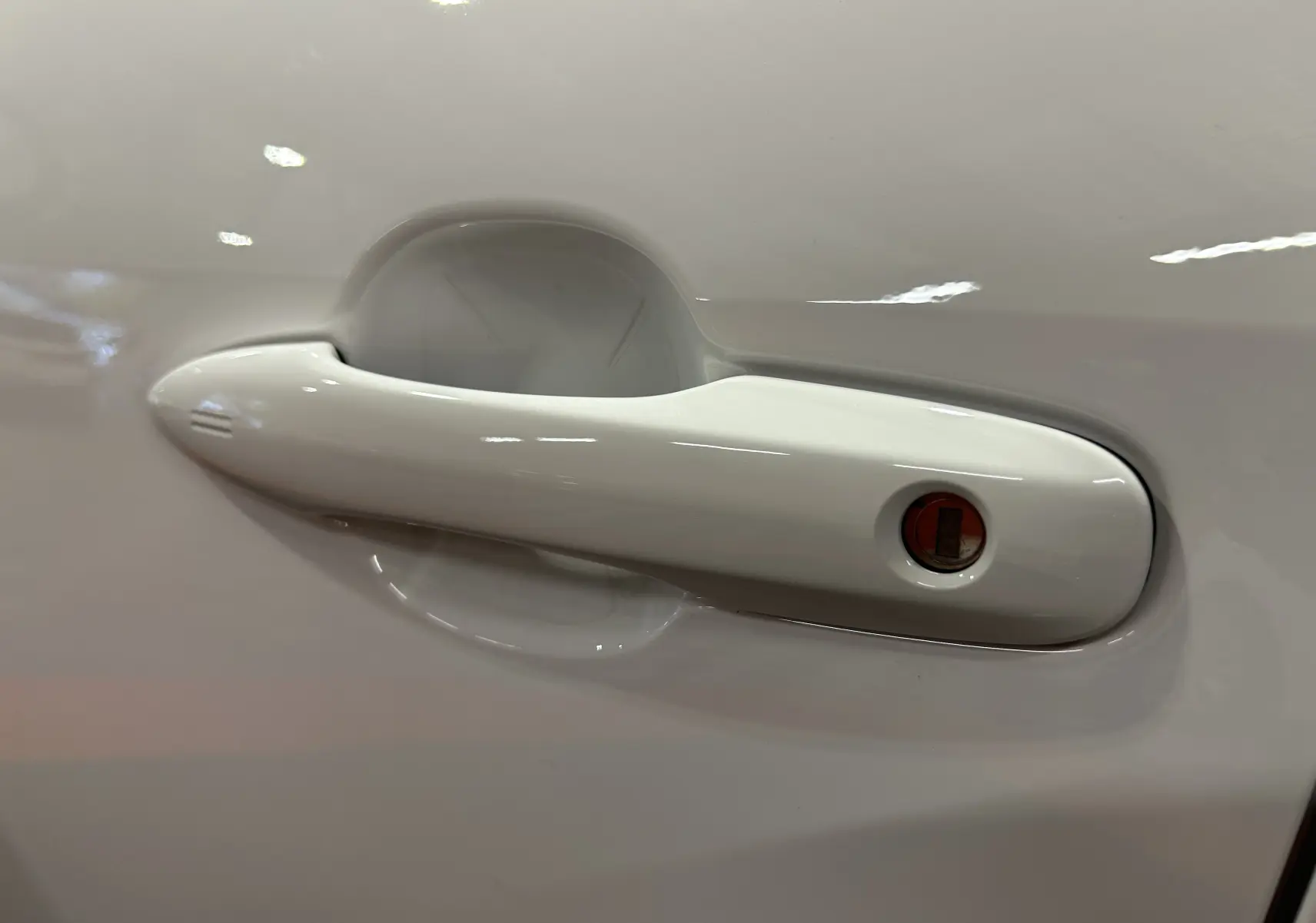 Poignée de porte blanche en gros plan sur le côté gauche d'une Toyota Yaris Cross 130 Design 2025 hybride.