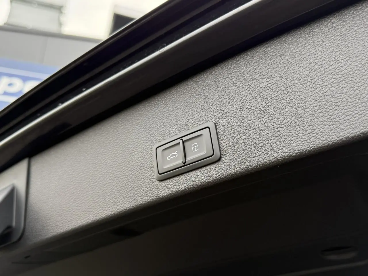 Boutons de commande du hayon électrique et de verrouillage intégrés dans le hayon noir du coffre d'un Audi Q2 35 TFSI S-Line.