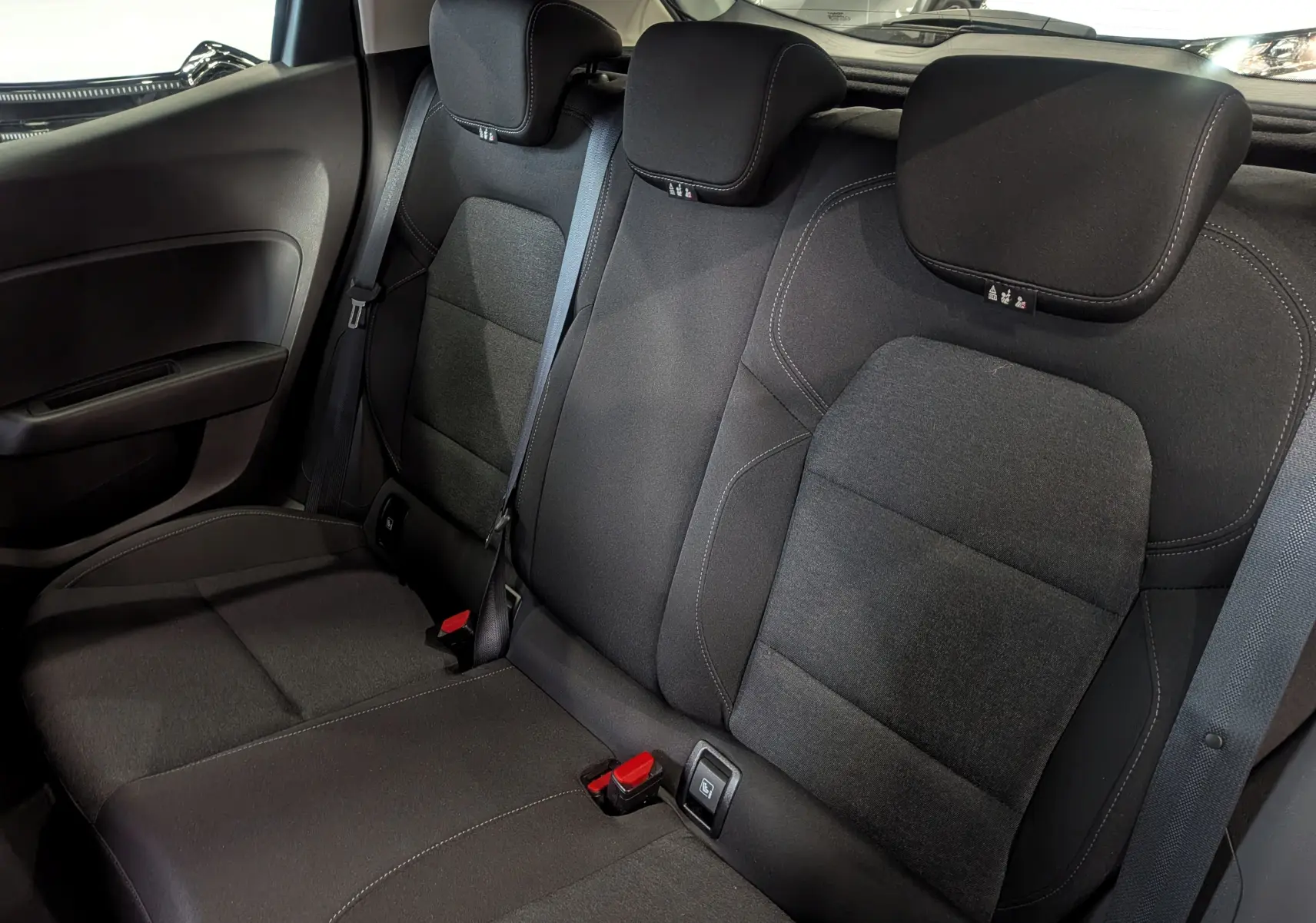 Vue intérieure des sièges arrière en tissu noir de la Renault Clio V Business 2021, avec ceintures de sécurité et appuie-têtes.