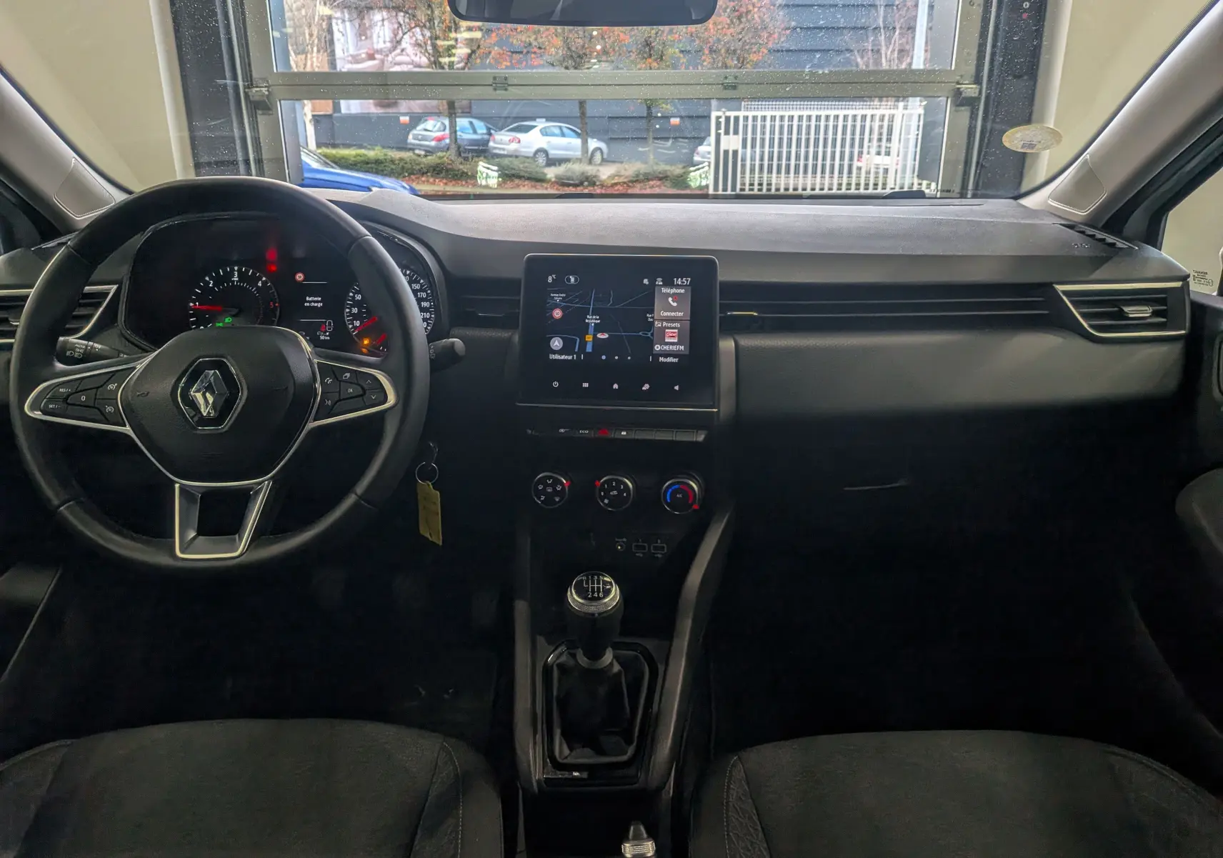 Vue intérieure avant de la Renault Clio V Business 2021, tableau de bord noir avec écran tactile et levier de vitesse manuel.