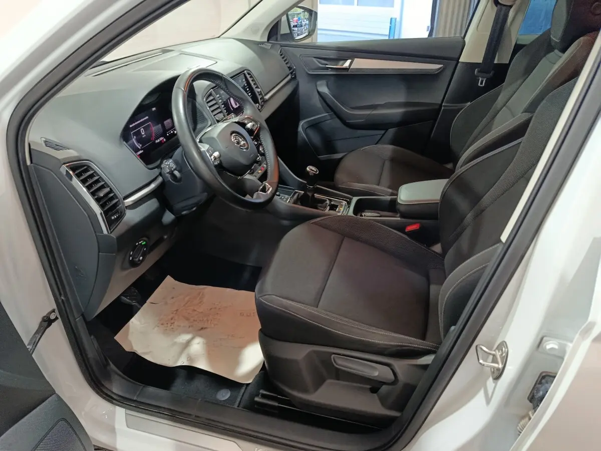 Intérieur avant droit du Skoda Karoq 2024 avec sièges noirs, volant cuir multifonctions et tableau de bord digital.