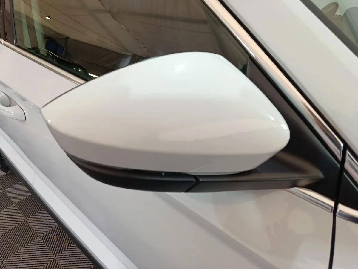 Rétroviseur côté gauche blanc du Skoda Karoq 2024 2.0 TDI, vue rapprochée sur la portière et la vitre.