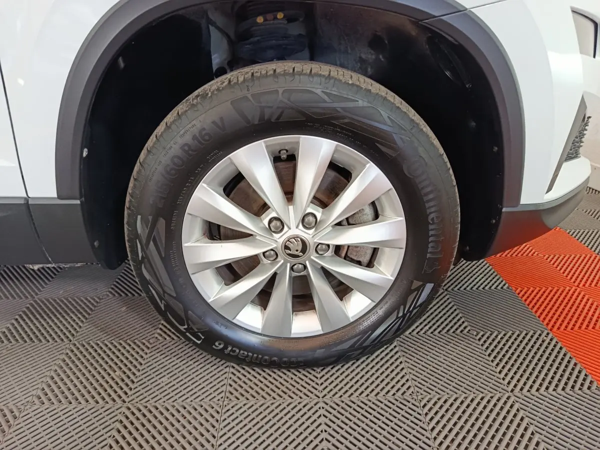 Gros plan sur la roue avant droite argentée d’un SKODA KAROQ blanc avec jante en alliage et pneu Continental.