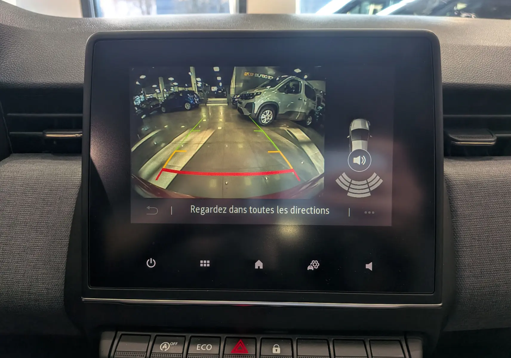 Écran central de la Renault Clio V Orange Valencia montrant l’affichage de la caméra de recul avec guidage et alertes sonores.