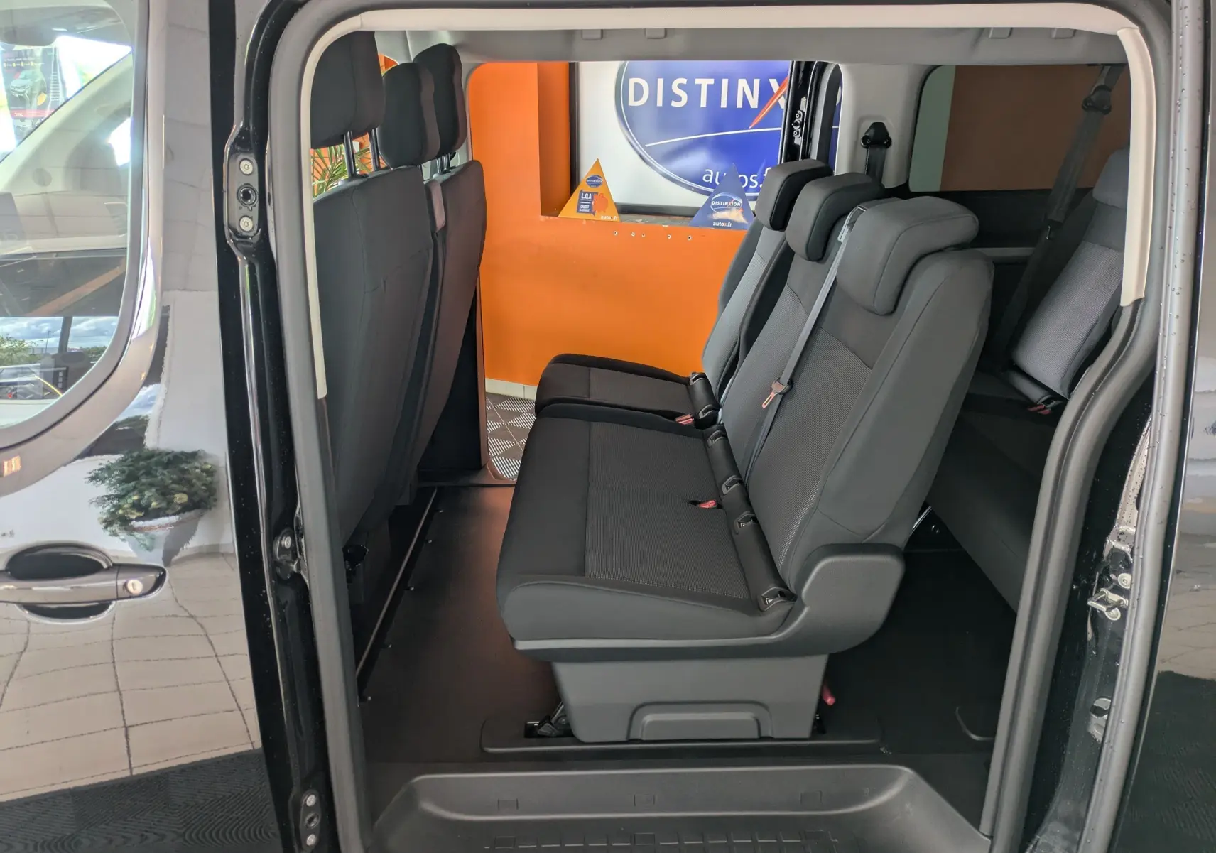 Vue latérale intérieure du Peugeot Traveller noir 2026, montrant les sièges passagers en tissu sur deux rangées.