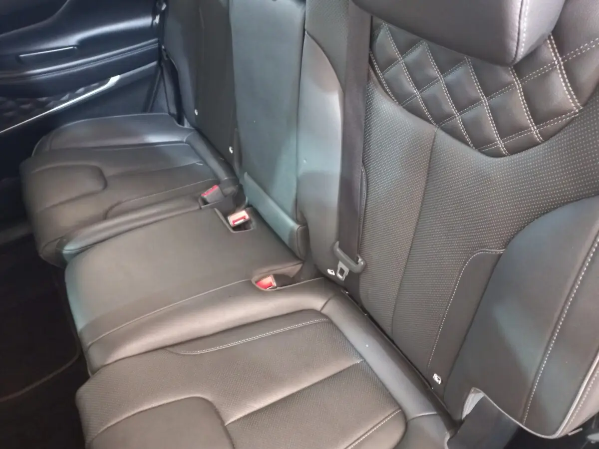 Vue rapprochée des sièges arrière en cuir noir du Hyundai Santa Fe 2021, avec surpiqûres et ceintures visibles.