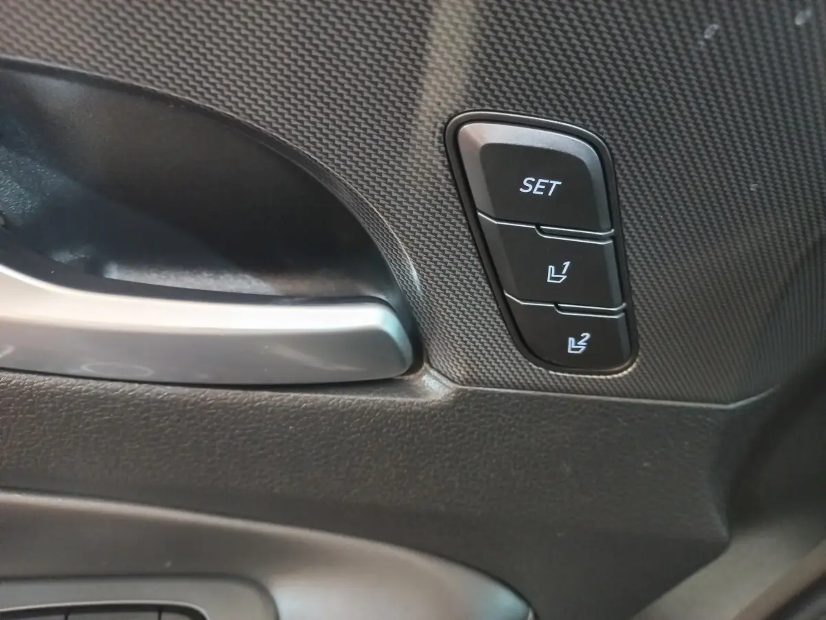 Gros plan sur la poignée intérieure et les boutons de réglage mémoire des sièges du Hyundai Santa Fe gris clair.