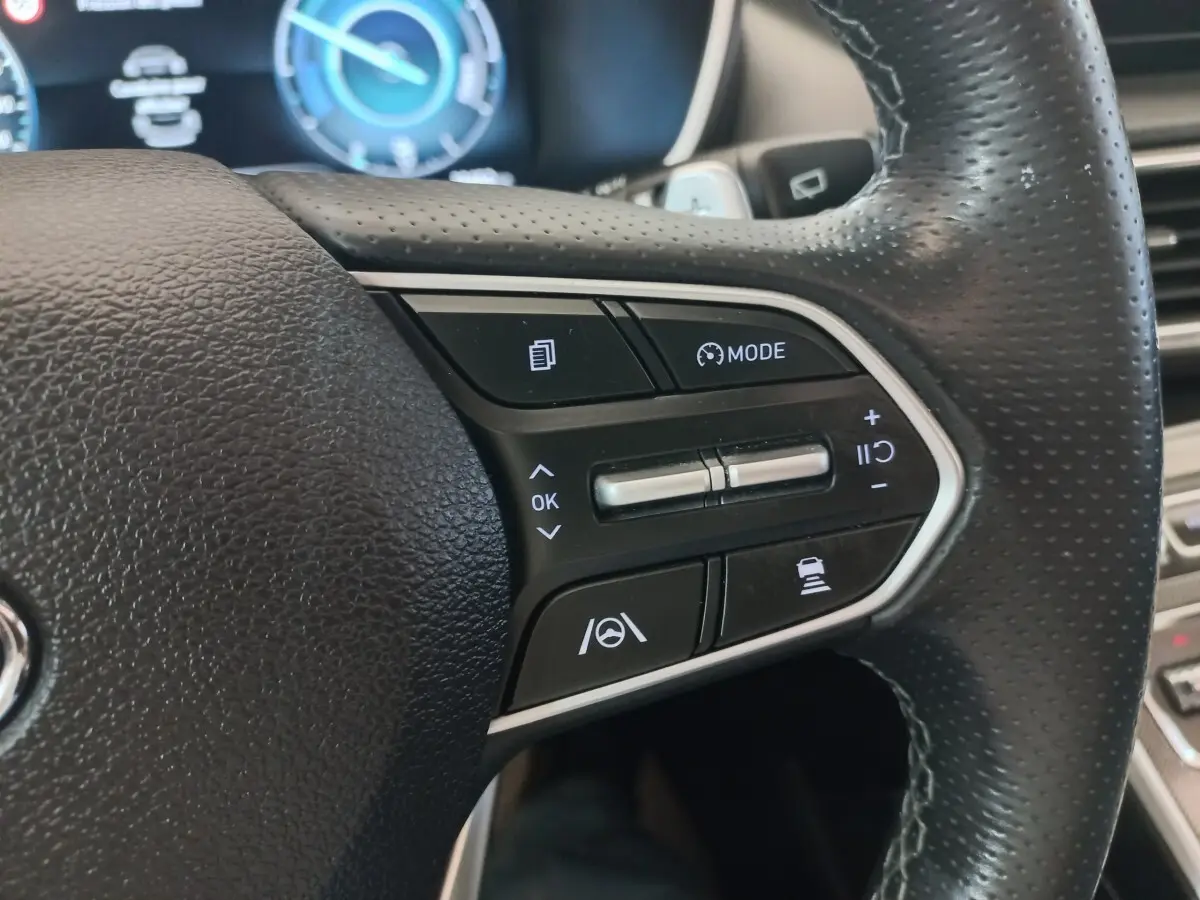 Gros plan sur les commandes multifonctions du volant cuir noir du Hyundai Santa Fe hybride rechargeable 2021.