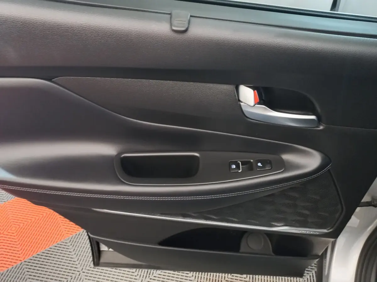 Gros plan sur la porte intérieure côté gauche noire avec commandes de verrouillage et haut-parleur Harman Kardon.