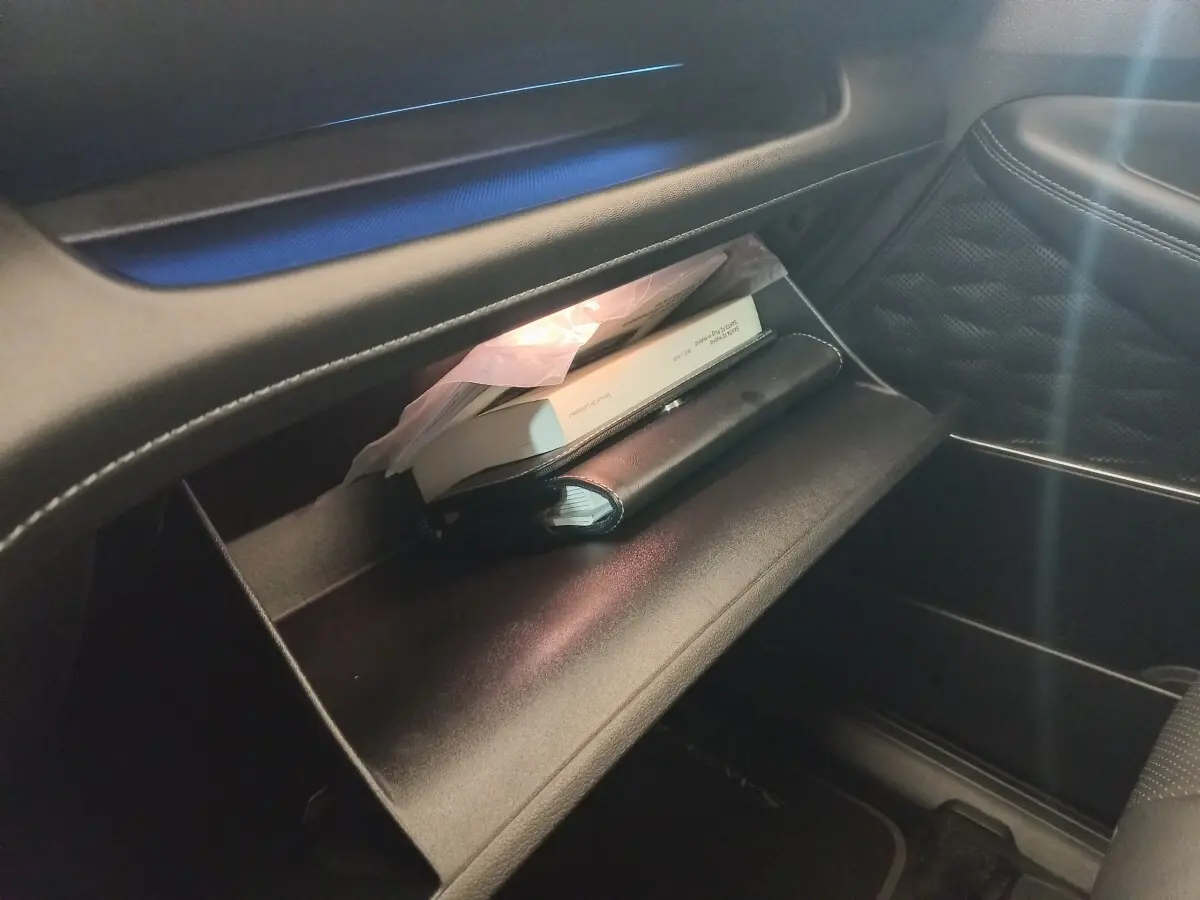 Intérieur du Hyundai Santa Fe hybride 2021, vue sur la boîte à gants ouverte avec documents et éclairage intérieur.