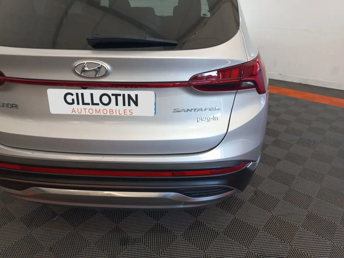 Vue arrière du Hyundai Santa Fe gris clair avec feux LED et logo plug-in visible sur un sol à motifs.