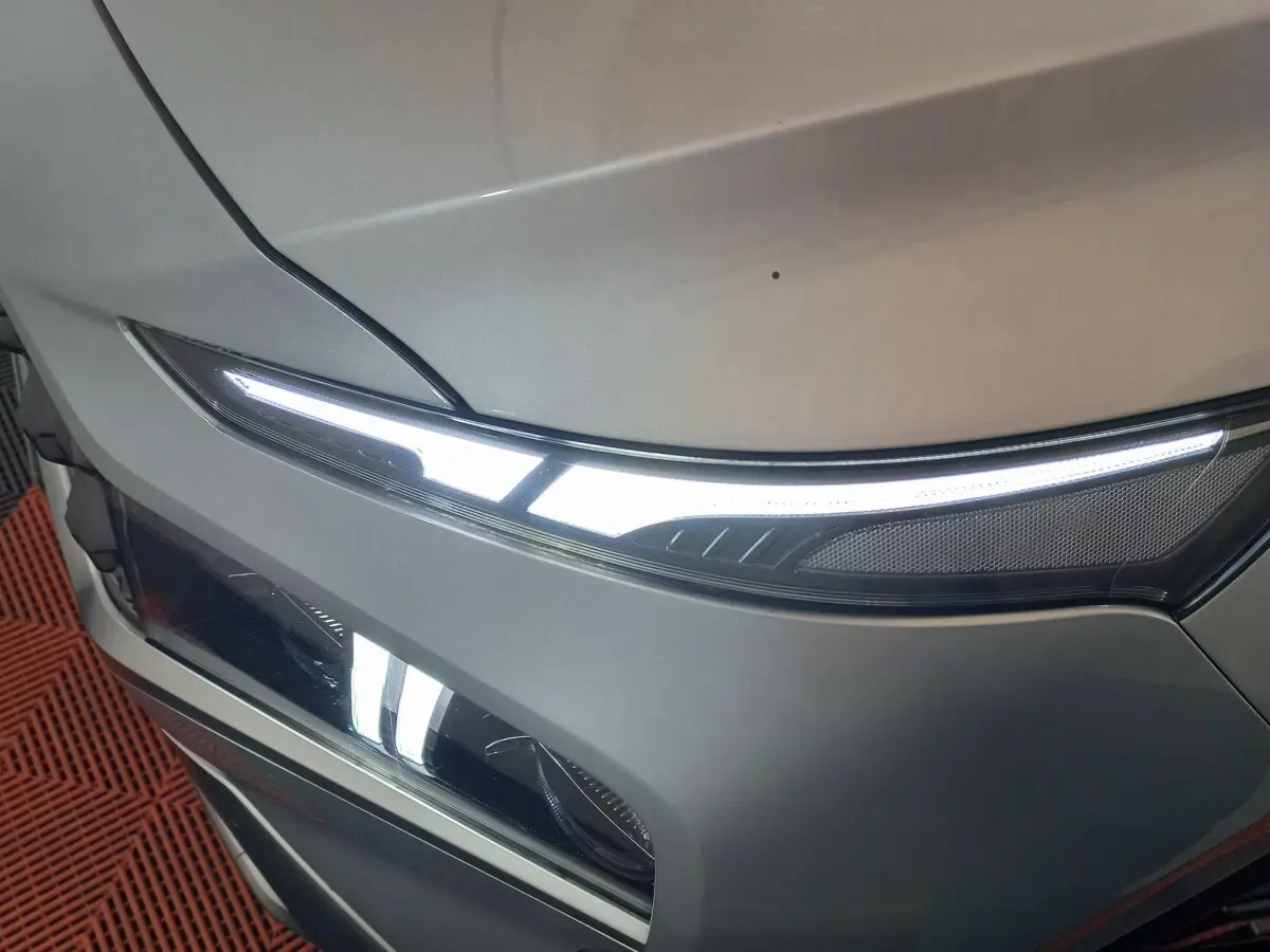 Gros plan sur le phare avant droit allumé d’un Hyundai Santa Fe gris clair, mettant en valeur son design LED fin et moderne.