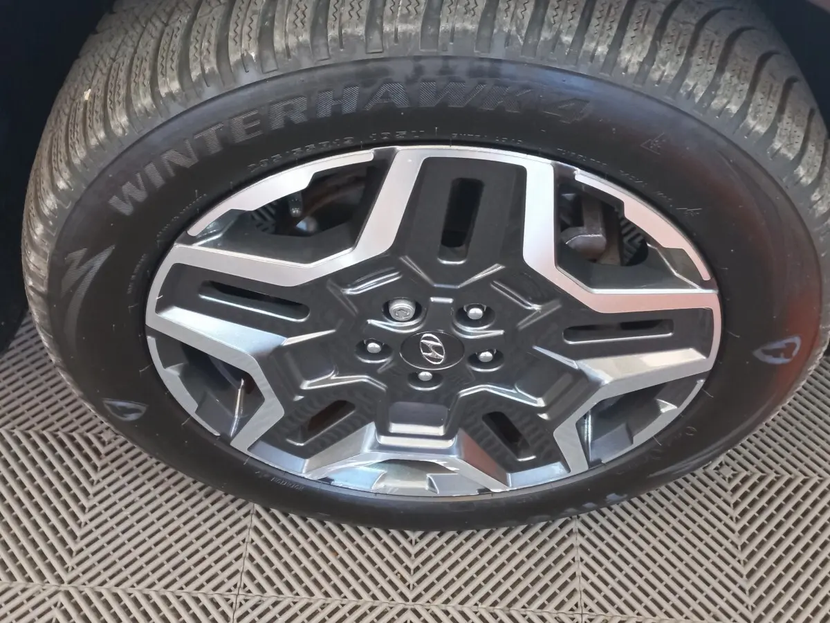 Gros plan sur la jante alliage grise et noire avec logo Hyundai, montée sur pneu hiver Winterhawk 4.
